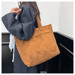 Close-up of brown corduroy tote bag showing ribbed texture and leather patch detail