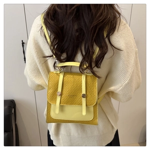 Detail of yellow PU leather backpack featuring crocodile texture and gold hardware on model