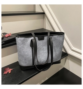 Close-up of contrast felt tote bag with premium black leather trim on a black step