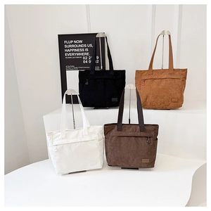 Detailed view of four corduroy tote bags in white, black, brown, and caramel with front pocket