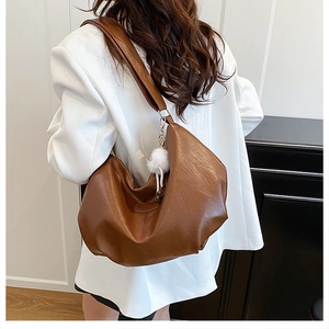 Sac hobo en cuir marron caramel avec large bandoulière et pendentif en peluche blanc