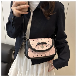 Détail du sac bandoulière rose plissé avec nœud noir et pendentif en cœur