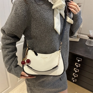 Chic white half-moon crossbody bag in lychee leather with black trim and cherry charm