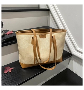 Detail of canvas tote bag with brown leather trim and dual handles on black stairs