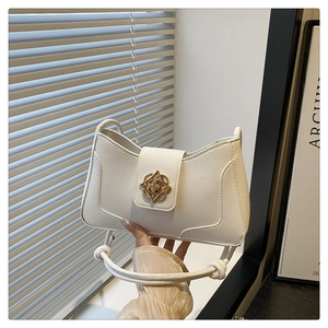 Détail d'un sac à main blanc crème avec boucle fleur dorée et poignée à nœud élégante