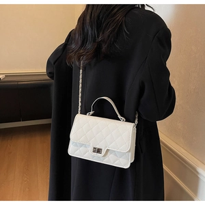 Close-up of quilted white crossbody bag with silver twist lock and chain strap detail