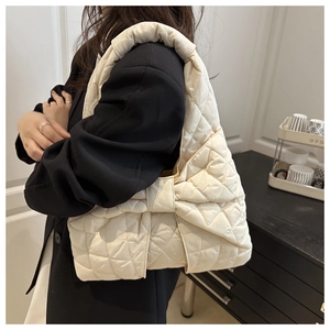 Detail of beige quilted shoulder bag featuring a puffy bow design and diamond stitching