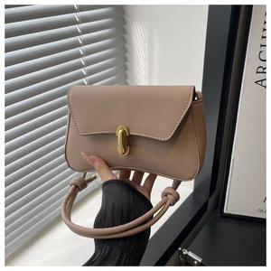 Dettaglio della borsa beige curva con chiusura girevole in oro e texture in pelle liscia fine