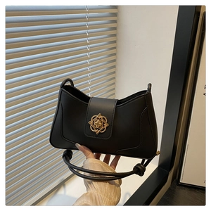 Détail d'un sac à bandoulière noir en demi-lune avec boucle en métal doré ajourée