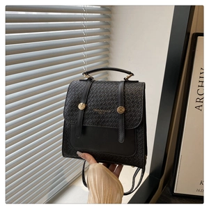 Detail of black woven backpack featuring dual leather straps and gold tidal buckle accents