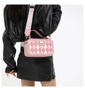 Detail of pink quilted camera bag with woven strap and gold hardware on model