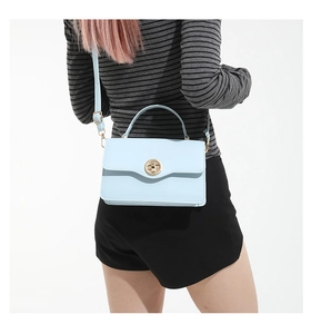 Mannequin portant un sac bandoulière bleu clair avec fermoir rotatif et sangle réglable