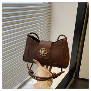 Détail du sac bandoulière rétro en cuir marron foncé avec boucle florale dorée