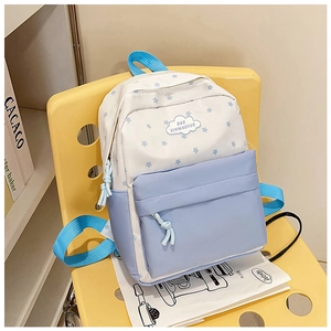 Détail du sac à dos scolaire bleu et blanc à motif d'étoiles avec patch nuage sur chaise