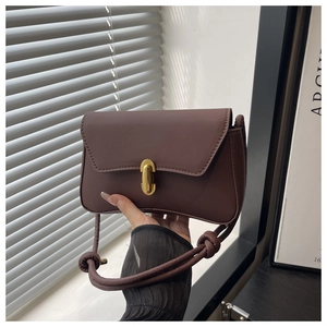 Dettaglio borsa a tracolla in pelle marrone con chiusura dorata e tracolla con nodo decorato