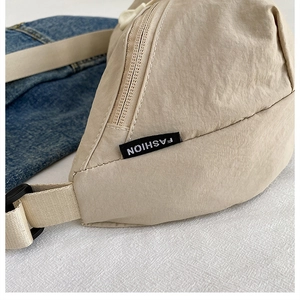 Close-up of beige nylon waist bag with adjustable strap and fashion label detail