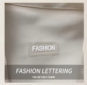 Detail of beige tote bag fabric showing a white silicone FASHION label and woven texture