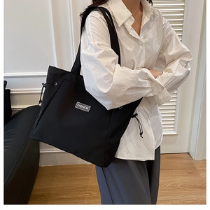 Close-up of black canvas tote bag with fashion label and adjustable side drawstrings