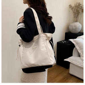 Detail of cream canvas tote bag with FASHION label and decorative side drawstrings