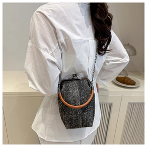 Detail shot of tweed crossbody doctor bag with round handle and metal chain on a model