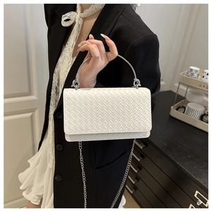 Detail of white woven leather texture with silver metal ring handle and chain strap