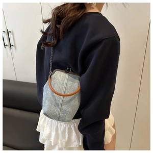 Detailed view of light blue denim bucket bag with vintage metal clasp and leather handle