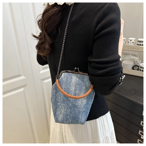 Detail of vintage denim crossbody bag with metal buckle and brown leather handle