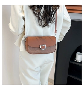 Detail of a brown and khaki flap shoulder bag with silver D-ring buckle and woven texture