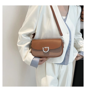 Detail of a brown leather and fabric patchwork shoulder bag with a silver D-buckle