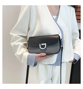 Close-up of contrast crossbody bag with matte black flap and silver D-buckle detail