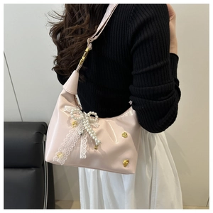 Detail of pink patent leather bag with lace bow, pearls and gold heart charms