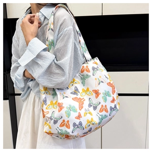 Mannequin portant un grand sac cabas en toile blanche avec des imprimés papillons colorés