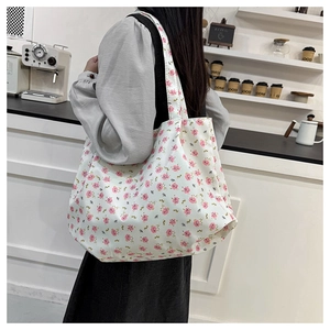 Detailed shoulder view of a floral canvas tote bag with pink rose patterns in a cafe setting