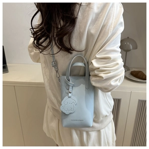 Detail of light blue crossbody bucket bag with cartoon puppy charm and fashion lettering