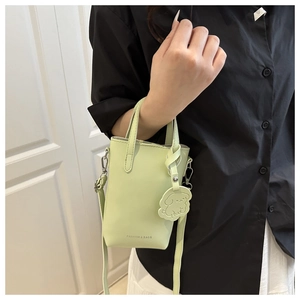 Detail of light green mini bucket bag with cute dog pendant and detachable strap