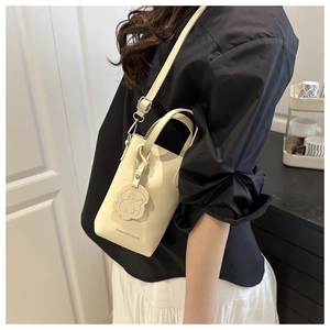 Detail view of off-white lychee pattern bucket bag with dog charm and metal clasp