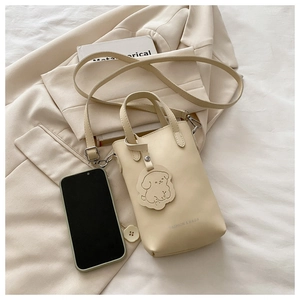 Detail of beige PU leather bucket bag showing smartphone capacity and dog pendant