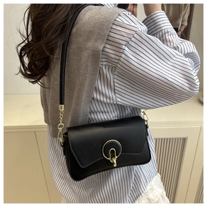 Vista lateral del bolso de hombro negro mate con hebilla dorada y cadena en la modelo