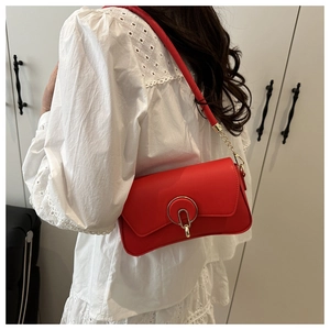 Close-up of vibrant red leather box bag with gold circular buckle and chain strap