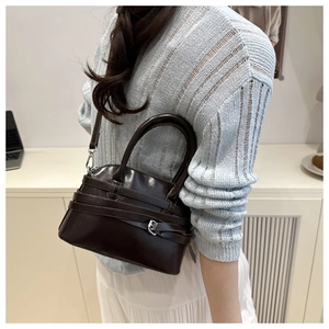 Detail view of dark chocolate leather handbag with wrap-around belts and silver buckles