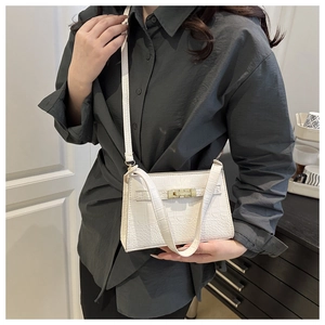 White croc-embossed women's bag worn as a shoulder bag featuring elegant gold clasp detail