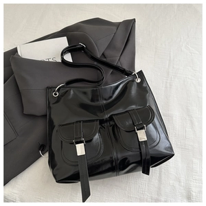 Detail of black glossy tote bag with dual front pockets and silver metal buckles