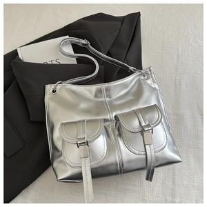 Detail view of metallic silver tote bag with buckle pockets on professional blazer