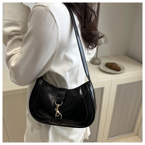 Détail du sac sous le bras en cuir verni noir avec boucle piston dorée de style vintage