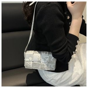 Detailsicht der silbergrauen geflochtenen Tasche mit Schlangenmuster und Leder-Schultergurt