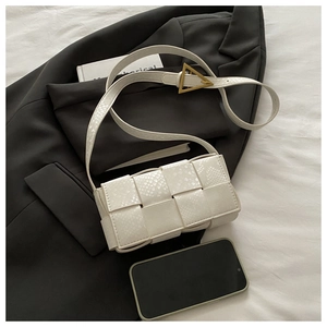 Close-up of white woven leather texture and golden triangle buckle on the handbag