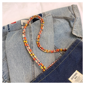 Dettaglio borsa in denim con tracolle colorate di perline ed etichetta su tessuto jeans