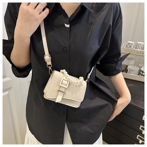 Close-up of woven crossbody bag featuring a pearl handle and chic leather buckle