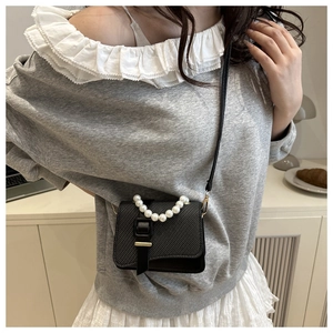 Detail of elegant black mini bag with woven texture and premium white pearl handle