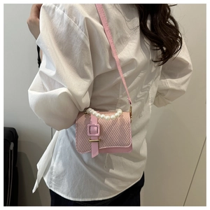 Pink woven mini crossbody bag with pearl handle worn by model over a white shirt